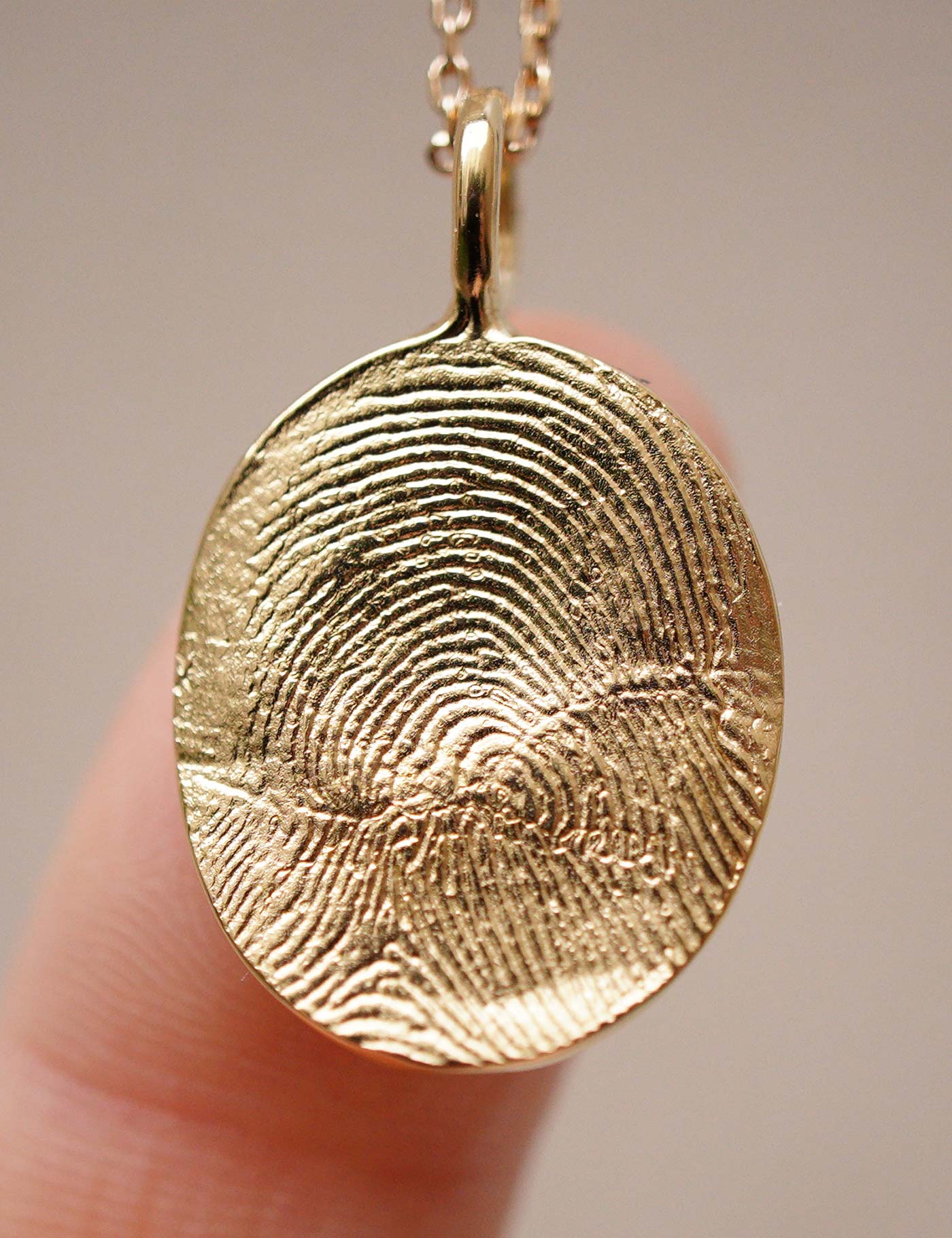 Médaillon personnalisé empreinte digitale de forme ovale et organique, plaqué or 24 carats, fabrication artisanale.